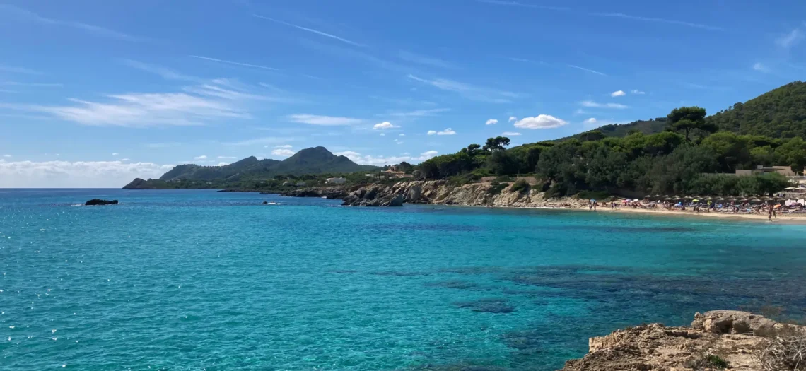 Mallorca: Ein Bild mit Wasser, Bäumen und Bergen im Hintergrund.