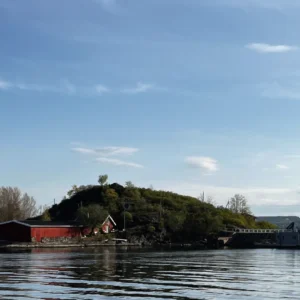 Im Vordergrund Wasser mit einem Gebäude und Hügel. Oslo Städtetrip