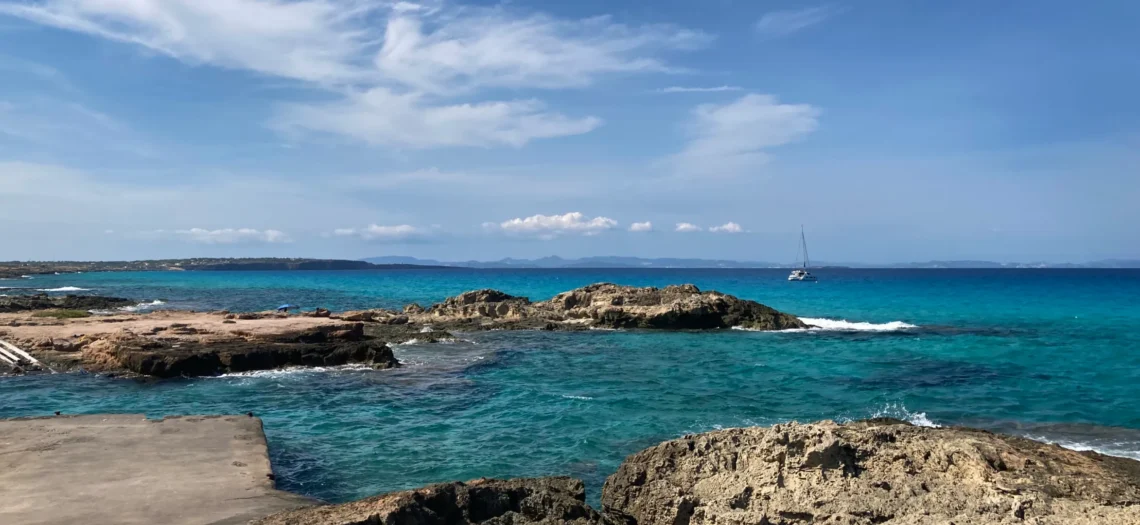 Formentera: Im Bild sieht man Wasser mit einem Boot im Hintergrund.