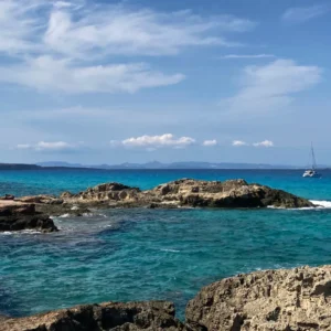 Formentera: Im Bild sieht man Wasser mit einem Boot im Hintergrund.