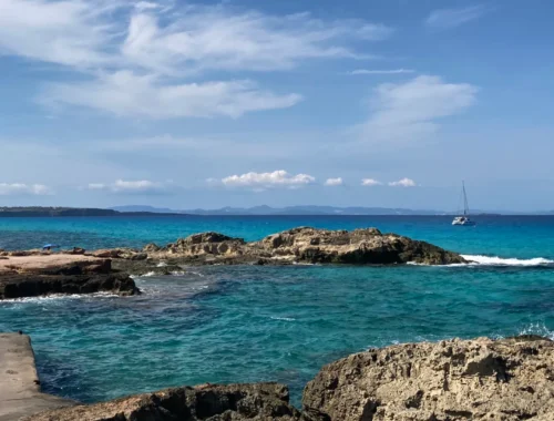 Formentera: Im Bild sieht man Wasser mit einem Boot im Hintergrund.