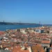 Lissabon: Eine Stadt mit roten Dächern und eine Brücke die über das Wasser führt.