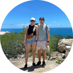 Zwei Personen auf einem Hügel mit Meer im Hintergrund.
