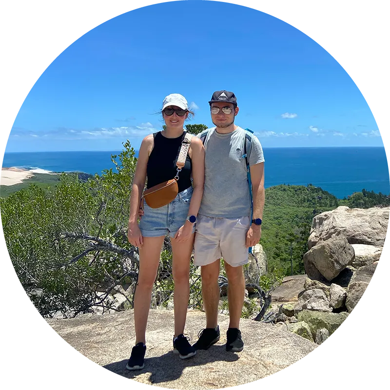 WIR SIND MAL REISEN: Zwei Personen auf einem Hügel mit Meer im Hintergrund.